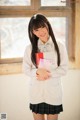 A young woman in a school uniform holding a book.